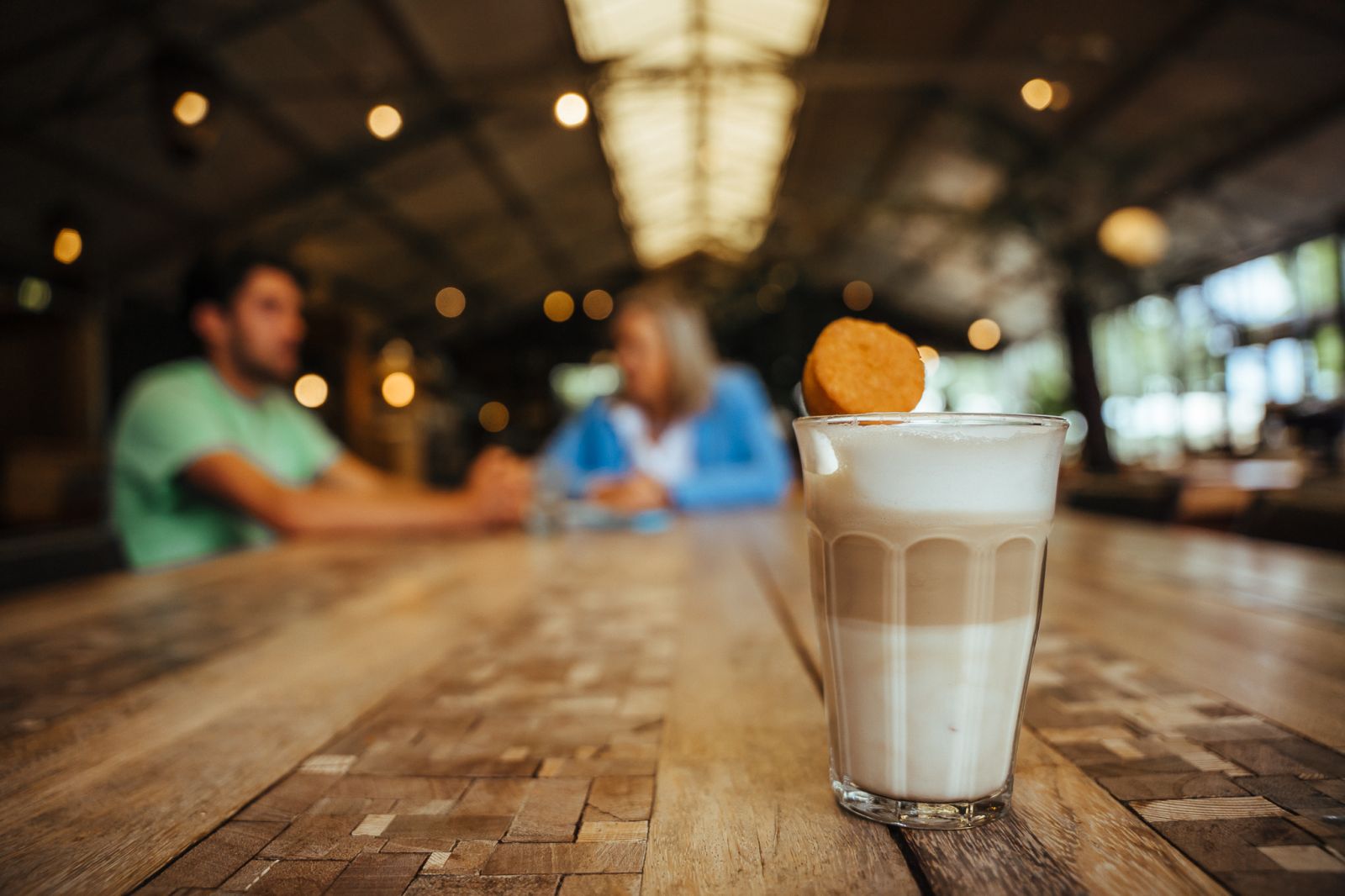 Koffie op de voorgrond en in de achtergrond een incompany training aan tafel met een man en vrouw